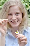 Happy young woman plucking petals from daisy