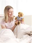 Woman with teddy in bed