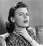 1940s PORTRAIT OF WOMAN HOLDING HER SORE THROAT WITH EXPRESSION OF DISCOMFORT AND PAIN