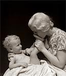 1930s MOTHER KISSING BOTTOM OF BABY'S FOOT