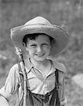 1930s SMILING BOY IN OVERALLS & STRAW HAT WITH FISHING POLE SLUNG OVER SHOULDER