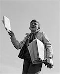 1960s PAPERBOY WITH STACK OF PAPERS UNDER ARM CALLING EXTRA! EXTRA!