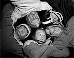 1960s FIVE BOYS IN HUDDLE WEARING HELMETS & FOOTBALL JERSEYS THE VIEW IS FROM INSIDE THE HUDDLE LOOKING UP