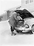 1950s MAN WINTER DRIVEWAY TRYING TO START FIX CAR HOOD UP