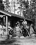 1920s - 1930s COUPLE IN FRONT OF LOG CABIN WOMAN SITTING ON PORCH RAILING MAN ON HORSE ALBERTA CANADA