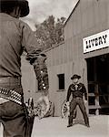 1950s - 1960s TV COWBOYS IN FRONT OF LIVERY STABLE READY TO DRAW PISTOLS IN GUNFIGHT