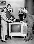 1950s - 1960s COUPLE  BUYING NEW CONSOLE TELEVISION FROM APPLIANCE SALESMAN