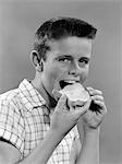 1950s BOY WITH CREW CUT EATING A SLICE OF BREAD