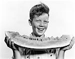 1940s - 1950s SMILING BOY HOLDING EATING LARGE SLICE OF WATERMELON
