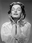 1950s WOMAN WEARING PEIGNOIR WITH EYES CLOSED HANDS HELD NEAR FACE ECSTATIC FACIAL EXPRESSION