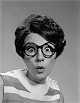 1960s PORTRAIT BRUNETTE WEARING DARK THICK ROUND EYEGLASSES WITH EYES WIDE OPEN