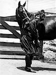 1900s - 1910s YOUNG WOMAN WITH UPSWEPT HAIR LIFTING FRONT LEG OF HORSE CHECKING CLEANING HOOF