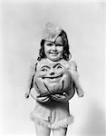1930s - 1940s HAPPY SMILING LITTLE GIRL IN COSTUME HOLDING A PAPIER-MACHE PUMPKIN HEAD