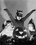 1950s 3 CHILDREN IN COSTUMES AROUND A CARVED PUMPKIN JACK-O-LANTERN