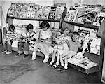 1950s GROUP OF 5 CHILDREN SITTING ON NEWSSTAND READING MAGAZINES COMIC BOOKS