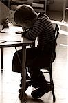 1970s BOY SITTING WRITING AT SCHOOL DESK