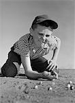 1950s - 1960s BOY PLAYING MARBLES KNEELING IN THE DIRT SQUINTING MISSING A FRONT TOOTH