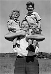 DES ANNÉES 1930, FILS DE TENUE DE PÈRE SOURIANT AVEC LE BASEBALL MITT & FILLE SUR SES ÉPAULES