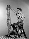 1950s BOY EATING JELLY TOAST SITTING ON LADDER STACKING UP TALL PILE OF TOAST FROM TOASTER