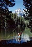 1960s MAN FISHING AT STRING LAKE GRAND TETON NATIONAL PARK WYOMING