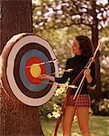 1970s WOMAN FEMALE ARCHER PULLING ARROWS FROM ARCHERY TARGET