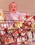 1960s HAPPY BABY SITTING INSIDE SHOPPING CART FULL OF GROCERIES