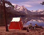 1970s OLDER COUPLE SITTING CAMPING BY RED TENT STANLEY LAKE IDAHO