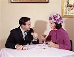 1960s COUPLE DRINKING COCKTAILS AT TABLE HUSBAND WIFE INDOOR