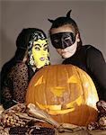 TWO YOUNG GIRLS IN WITCH AND BLACK CAT HALLOWEEN COSTUMES WITH CARVED JACK-O-LANTERN PUMPKIN S