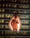 1970s BUSINESSMAN SMOKING CIGARETTE SUPERIMPOSED  ON EXTERIOR OFFICE BUILDING WINDOW