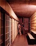 1970s PRISON INTERIOR PRISONER ESCORTED TO JAIL CELL BY POLICE GUARD