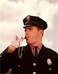 1960s PORTRAIT MAN POLICEMAN TRAFFIC COP BLOWING WHISTLE