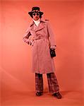 1970ER JAHRE AFRIKANISCHE AMERIKANER IN TAN TRENCHCOAT AVIATOR SONNENBRILLE MÜTZE HANDSCHUHE ROLLKRAGEN PLAID BELLBOTTOM PLAID HOSE