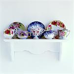 2000s FLORAL PATTERNED TEACUPS AND SAUCERS ON MANTELPIECE WHITE SHELF
