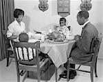 1960s AFRICAN-AMERICAN FAMILY AT DINING TABLE WITH TURKEY SAYING GRACE PRAYING