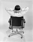 1960s MAN FROM BEHIND SITTING IN OFFICE EXECUTIVE CHAIR HANDS CLASPED BEHIND NECK