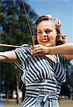 1940s - 1950s SMILING TEEN GIRL ARCHER WEARING BLUE AND WHITE STRIPED DRESS SHOOTING AIMING BOW AND ARROW