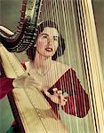 1940s - 1950s WOMAN PLAYING HARP WEARING RED VELVET GOWN