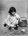 1920s - 1930s GIRL SITTING NEXT TO BASKET ON STRAW PLAYING WITH CHICKS