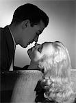 1940s - 1950s MOVIE STAR STUDIO STYLE ROMANTIC COUPLE EMBRACING ON SOFA ABOUT TO KISS HUSBAND SILHOUETTE WIFE LONG BLOND HAIR