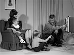 1960s FAMILY MOTHER FATHER SON DAUGHTER WATCHING TELEVISION IN LIVING ROOM INDOOR