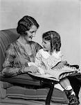 1920s - 1930s MOTHER & DAUGHTER SMILING SITTING IN CHAIR READING BOOK