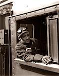 1920s - 1930s - 1940s RAILROAD TRAIN ENGINEER LOOKING OUT WINDOW OF LOCOMOTIVE CAB DRIVING THE STEAM ENGINE