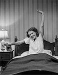 JEUNE FEMME DES ANNÉES 1940 EN LIT ÉTIREMENT WAKING UP