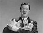 1960s SMILING MAN HOLDING MONEY BAGS AND  BUNDLES OF CASH