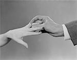 1960s MALE  HAND SLIPPING ENGAGEMENT RING ONTO FEMALE HAND