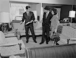 1960s FURNITURE STORE SALESMAN TALKING TO COUPLE