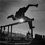 DES ANNÉES 1970 SUIVI DE RAYONS DE SOLEIL À TRAVERS LA SILHOUETTE DE L'HOMME SAUTANT CHAMP OBSTACLE