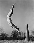 1940ER JAHRE MÄNNLICHE CHEERLEADER SPRINGEN JUBELNDEN MEGAPHON AUF ERDEN