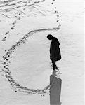 1970s OVERHEAD VIEW OF WOMAN MAKING CIRCULAR TRACKS IN WINTER SNOW OUTDOOR